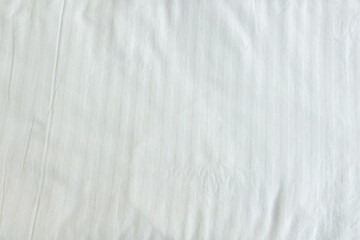 Soft crumpled white cotton fabric textile with subtle striped texture creating a clean background