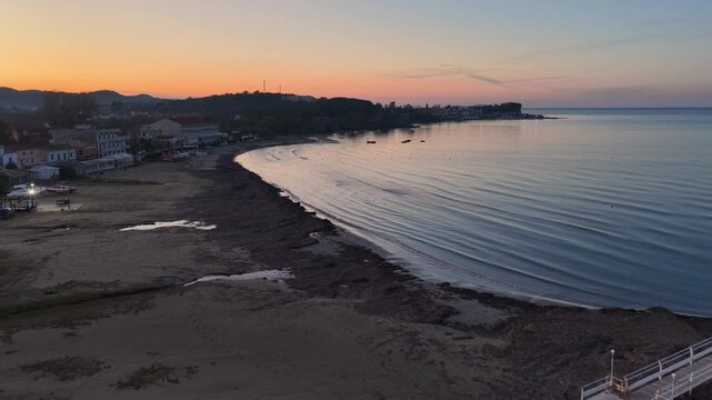 Panoramic aerial drone shot of Roda sandy beach and coastline during a vibrant orange sunset in Corfu island