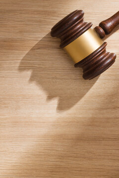 A judge's gavel on light wooden background in soft sunlight. Represents courtroom authority and legal decisions. Closeup view with copy space.