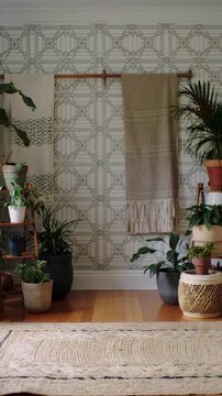 Vertical video: Panning camera moving right highlighting wall display with beige textile and plants