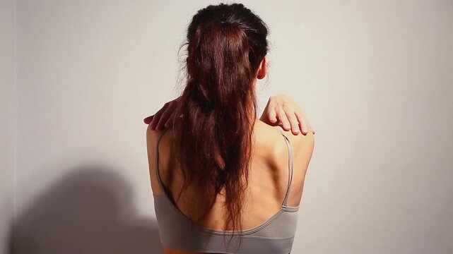 Health sport body woman doing stretching exercises for shoulders, scapula and healthy upper back, attractive body lifestyle. Fit naked muscles brunette model in bra on isolated studio light. Back view