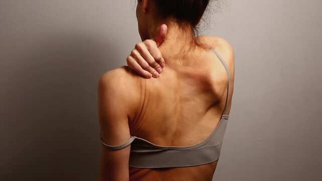 Health sport body woman doing massage with hand her shoulder, neck, upper back. Fit naked muscles model in bra isolated in studio light with copy space. Back view closeup