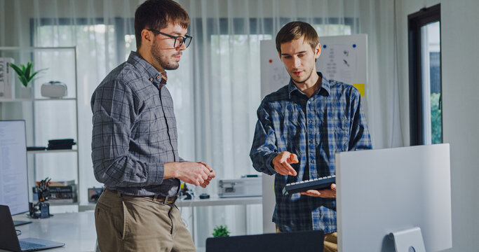 Team adult male engineer collaborate on robotic hand project using AI code solutions machine learning at tech workspace. Artificial intelligence interface, collaboration support prototype development.