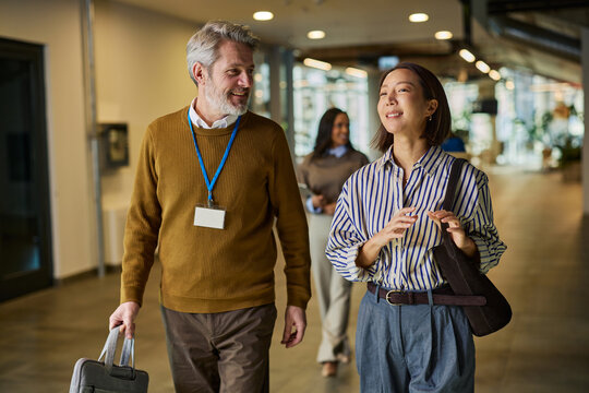 Diverse business colleagues walking and chatting in a modern office hallway during a conference