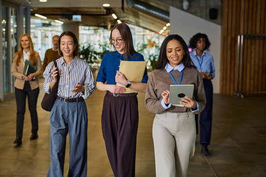 Diverse business women walking together at a modern office conference and networking event