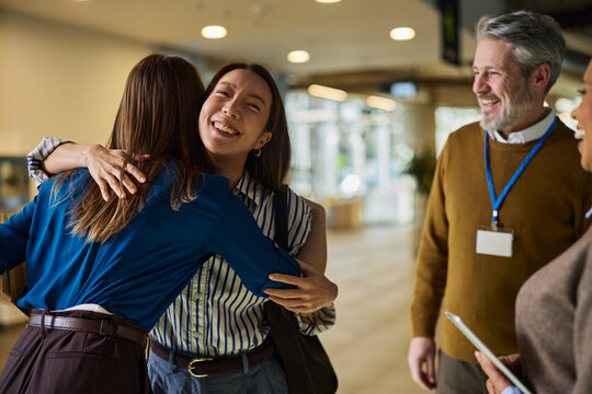 Diverse business people greeting and hugging in a bright conference lobby before a meeting