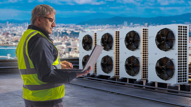 Building climate systems management. HVAC engineer inspects rooftop air conditioning units with laptop, monitoring cooling equipment performance and facility energy efficiency.