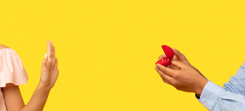 Declining proposal. Indian woman refusing to take engagement ring rejecting boyfriend, standing over yellow background, studio shot. She said no