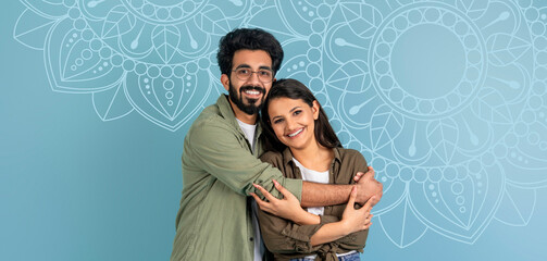 A couple stands together smiling in front of a blue wall featuring a mosaic design. They embrace each other and seem joyful in a bright space during the day. © Prostock-studio