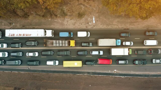 Traffic congestion along the highway during rush hour in October with diverse vehicles and a backdrop of autumn foliage