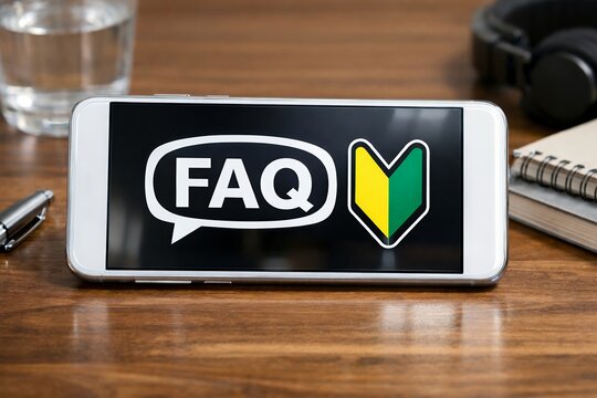 机に置かれたスマートフォンの画面に表示されたFAQの文字と初心者マークの合成写真