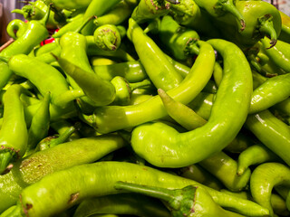 fresh green chili peppers piled together at market closeup showing vibrant spicy vegetables commonly used in cooking, healthy food preparation and natural organic ingredients