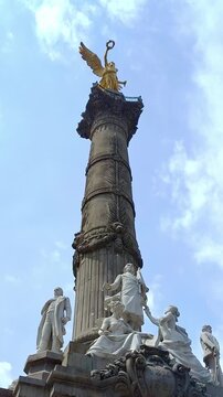 Low angle view of the Monumento a la Independencia featuring the gold Nike statue and marble sculptures of local heroes.