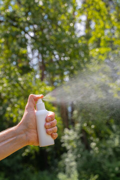 Hand spraying insect repellent outdoors
