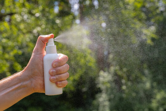 Hand holding bug spray for insect repellent outdoors