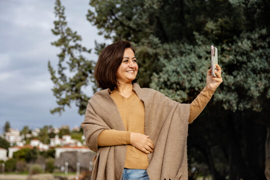 Woman taking selfie outdoors with smartphone