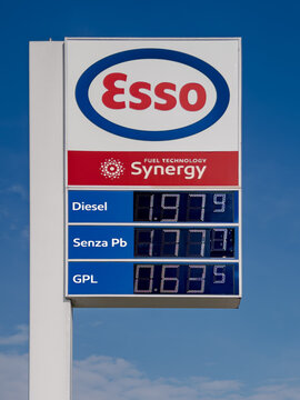 Italy - March 9, 2026: Sign display with increased fuel prices following the US-Iran conflict. Esso  fuel station sign display fuel price against the blue sky