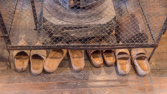 Wooden clogs and rustic stove on aged wooden floor
