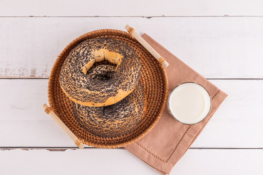 Bagels with poppy seeds and glass of milk on table