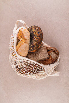 Assorted breads in reusable net bag on neutral background