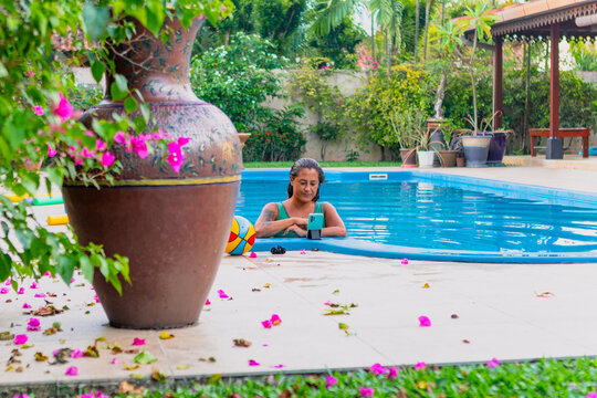 Woman relaxing by the pool and using smartphone