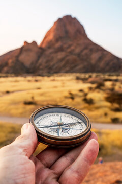 Hand holding compass with Spitzkoppe in Namibia