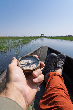 Hand holds compass in Okavango Delta boat journey