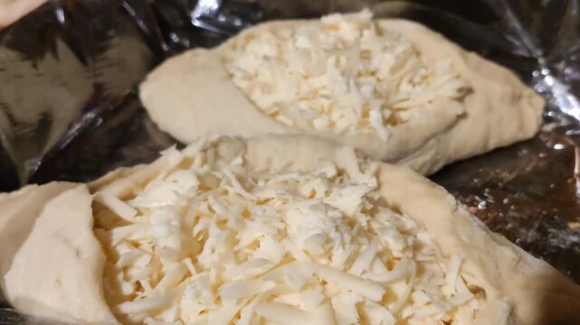 Homemade raw khachapuri bread with rich cheese filling. Traditional culinary heritage and cozy homemade cooking process.