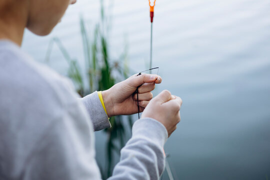 Teenage boy prepares fishing line by the water
