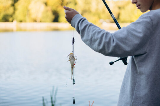 Teenage boy holding a fish by a serene lakeside