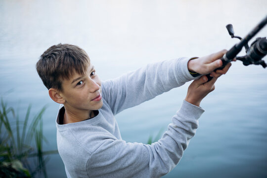 Teenage boy casting a fishing line near the water