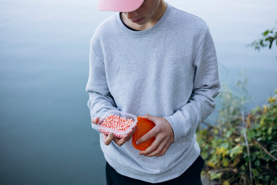 Teenage boy preparing fishing bait by the lakeside