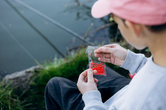 Teenage boy preparing bait for fishing at lakeside