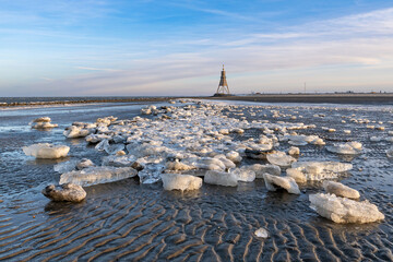 Wadden Sea in Cuxhaven, Germany on a frosty winter day with the Kugelbake, a historic aid to navigation at the northernmost point of Lower Saxony, in the background