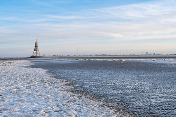 Wadden Sea in Cuxhaven, Germany on a frosty winter day with the Kugelbake, a historic aid to navigation at the northernmost point of Lower Saxony, in the background