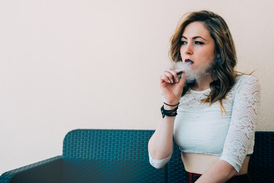 Woman smoking a cannabis joint indoors with relaxation
