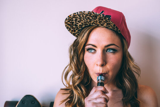 Woman enjoying cannabis with a vape pen indoors