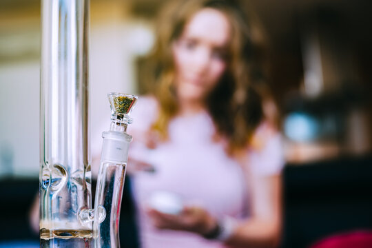 Woman with cannabis and glass pipe in focus