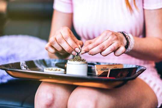 Woman rolling a joint with cannabis and marijuana tools
