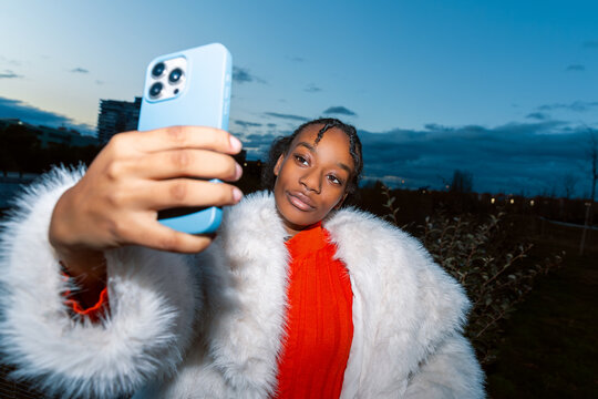 Gen Z girl taking a selfie in a stylish fur coat