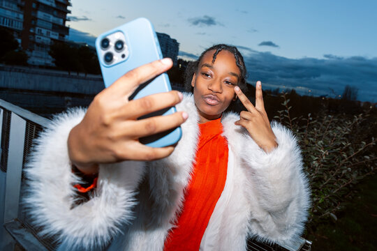 Young woman taking selfie with smartphone outdoors