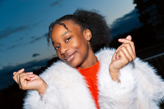 Gen Z girl in vibrant fur coat smiling confidently