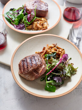 Sliced chuck steak with salad, mushrooms and wine.