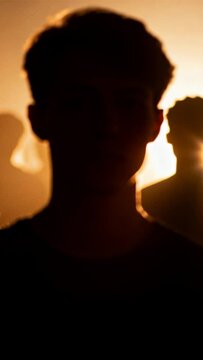 Vertical video: Shifting rear light revealing face of man in dark tee tilting head in studio haze