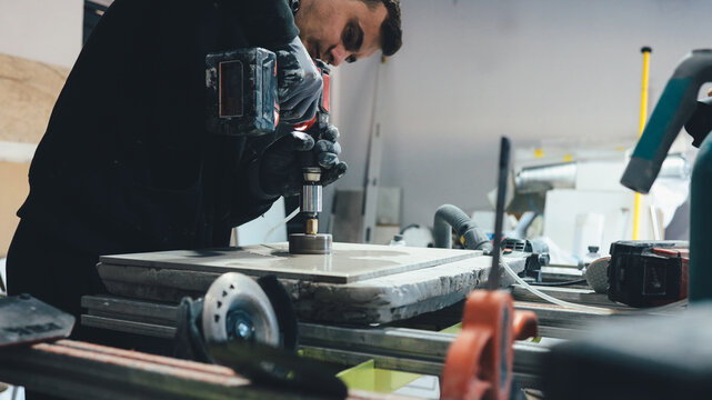 Craftsman precisely drills hole in stone slab with diamond core bit and power drill