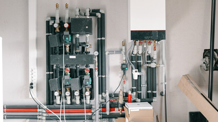 Modern central heating system manifold with pumps, valves, and gauges in a utility room