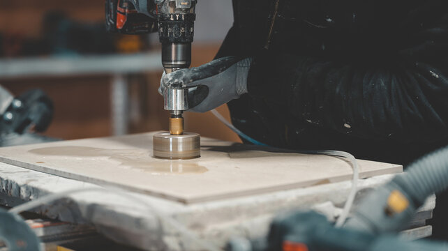 Close-up of a worker using a diamond core drill bit to cut a hole in a tile