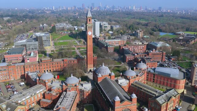Aerial video featuring the Old Joe clock tower at the University campus of Birmingham and the city skyline covered in thin fog. 