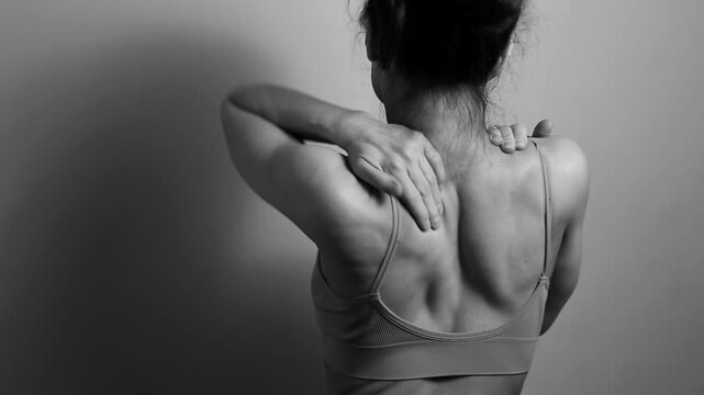 Sport body woman doing stretching exercises for shoulders, scapula and healthy back, fitness body lifestyle. Fit naked muscles model in studio with copy space. Back view. Black and white, monochrome