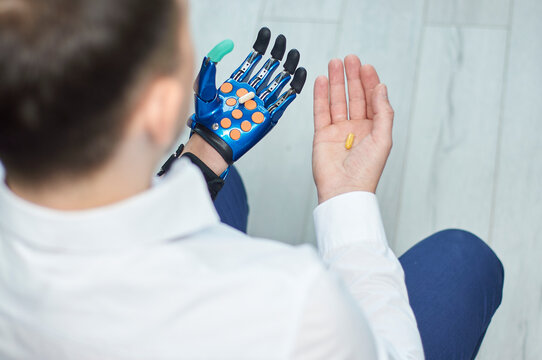 Close up of a bionic prosthetic hand holding a small yellow medicine capsule, concept of smart healthcare and precision medical technology